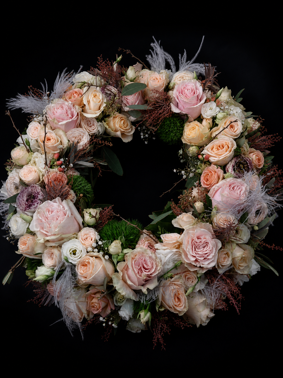 Floraler Trauerkranz aus Rosen in Rosé und Creme vor schwarzem Hintergrund